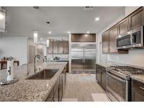 A stylish kitchen with granite countertops, stainless steel appliances, and sleek wood-look flooring at 6790 Tangled Vines Ave, Las Vegas, NV 89139