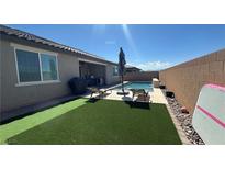 Backyard pool with lounge chairs and synthetic grass provides a relaxing outdoor oasis at 716 Cadence View Way, Henderson, NV 89011