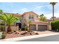 Elegant two-story home with a three-car garage and desert landscaping featuring palm trees at 8205 Taos Paseo Ave, Las Vegas, NV 89128