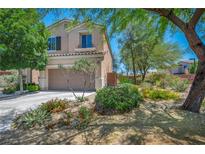 Charming two-story home with a well-manicured front yard, lush trees, and a spacious driveway leading to a two-car garage at 10692 Tulip Valley Rd, Las Vegas, NV 89179