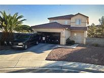 Two-story home with desert landscaping, a driveway, and a two-car garage with vehicles in the driveway at 6024 Ripple Cloud Ct, North Las Vegas, NV 89031