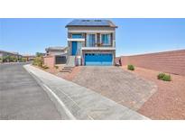 Inviting two-story home with a blue garage door, solar panels, and a stone driveway at 7828 Bright Lodge St, Las Vegas, NV 89139