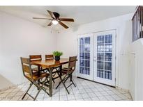 Bright dining room features a wooden table, four chairs, a ceiling fan and glass panel doors at 875 Rhinegold Way, Las Vegas, NV 89110
