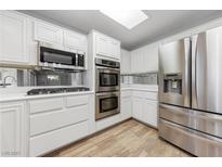 Bright kitchen features stainless steel appliances, white cabinets, and wood-look flooring at 9917 Arbuckle Dr, Las Vegas, NV 89134