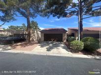 Home featuring a private entrance, attached garage, and desert landscaping on a sunny day at 1850 Camino Verde Ln, Las Vegas, NV 89119