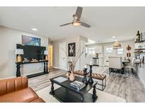 Bright living room with ceiling fan and view into dining area and kitchen with white cabinets at 445 Concord Way, Henderson, NV 89015