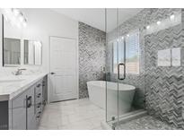 Modern bathroom featuring a soaking tub, glass shower, double vanity, and stylish tile accents at 600 Beresford Ave, Las Vegas, NV 89123