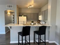 A cozy kitchen featuring gray cabinetry, a white countertop bar with seating, and modern appliances at 1830 N Buffalo Dr # 2022, Las Vegas, NV 89128