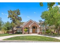Stunning two-story brick home with a well-manicured lawn and mature trees on a sunny day at 3102 La Mirada Ave, Las Vegas, NV 89120