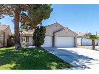 Charming single-story home with a well-manicured lawn, mature tree, and a two-car garage at 1409 Basin Brook Dr, North Las Vegas, NV 89032