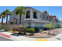 Charming gray townhome showcasing balconies, a two-car garage, and appealing landscaping with palm trees and flowering bushes at 295 Callen Falls Ave # 2225, Henderson, NV 89011