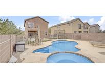 Backyard view of a kidney-shaped pool and outdoor seating area with wrought iron fence and light-colored stucco homes at 482 Painted Sage Ct, Henderson, NV 89015