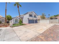 Two-story home featuring a two-car garage, a well-manicured lawn and palm trees on a sunny day at 4871 La Princesa Ct, North Las Vegas, NV 89031