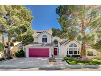 Charming two-story home with a well-manicured front yard, mature trees, and a vibrant red garage door at 7109 Deepriver Cir, Las Vegas, NV 89129