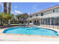 Backyard features a sparkling blue pool and spa combo with lush landscaping and a covered patio at 9585 Teton Diablo Ave, Las Vegas, NV 89117