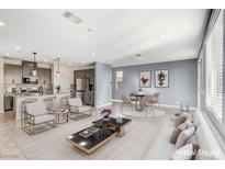 Inviting living space with modern furniture, adjacent kitchen, and neutral tones at 9886 Alpine Style Dr, Las Vegas, NV 89166