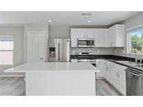 Modern kitchen with white cabinets, stainless steel appliances, and a quartz countertop island at 5116 Iron Crossing Ave, Las Vegas, NV 89131