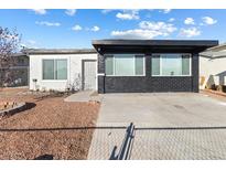 Single story home with a mix of white and black brick exterior and easy to maintain gravel landscaping at 704 Slayton Dr, Las Vegas, NV 89107