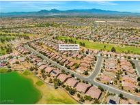 Wide aerial view of the community featuring lush landscaping, mountains, and tile roof homes at 7669 Fieldfare Dr, North Las Vegas, NV 89084
