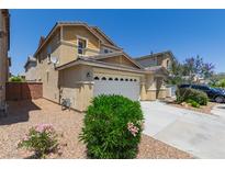 Two-story tan home with a two car garage, landscaping and a paved driveway at 104 Big Cliff Ave, North Las Vegas, NV 89031