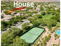 An aerial view featuring a tennis court, pool, and house in a well landscaped neighborhood with many trees at 11074 Caramel Crest Ct, Las Vegas, NV 89135