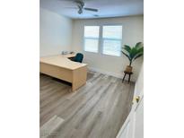 Bright office with large desk, ceiling fan, wood-look floors, and two sunny windows overlooking the outdoor view at 11074 Caramel Crest Ct, Las Vegas, NV 89135