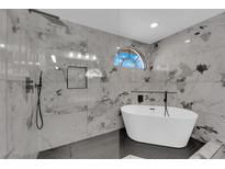Luxurious bathroom featuring a modern soaking tub, tiled shower with marble accents, and stylish fixtures at 1611 Buffalo Trail Dr, Henderson, NV 89014
