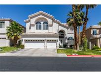 Beautiful two-story home featuring a three-car garage, manicured lawn and mature palm trees against a brilliant blue sky at 2090 Eaglepath Cir, Henderson, NV 89074