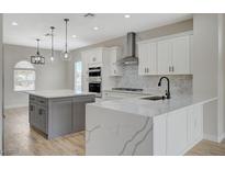 Bright open kitchen boasts white cabinets, stainless appliances, and an island with marble countertop and pendant lighting at 2603 Savannah Springs Ave, Henderson, NV 89052