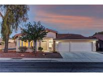 Charming single-story home featuring a two-car garage, desert landscaping, and a tile roof at sunset at 2725 Cool Lilac Ave, Henderson, NV 89052