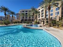 Beautiful community pool surrounded by palm trees and multi-story condo buildings on a sunny day at 29 Montelago Blvd # 336, Henderson, NV 89011