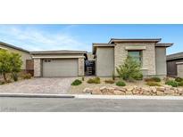 Charming single-story home featuring a stone facade, desert landscaping, and brick driveway at 977 Edinburgh Fields Ct, Las Vegas, NV 89138