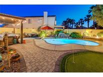 Inviting backyard pool with mature trees, a waterfall feature, an outdoor kitchen, and a putting green at 1028 Dodger Blue Ave, Las Vegas, NV 89123