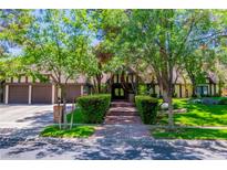 Charming home featuring mature trees, a brick walkway, and an attached three-car garage at 108 Quail Run Rd, Henderson, NV 89014
