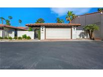 Attached two-car garage with white door, brick trim, and red tile roof, nestled among palm trees and white brick walls at 2104 Plaza De La Candela, Las Vegas, NV 89102