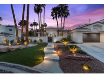 Beautiful home featuring manicured landscaping, an illuminated walkway, and mature palm trees in a desert setting at 219 Windsong Dr, Henderson, NV 89074