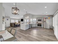 Open kitchen and living space featuring stainless appliances, island, and stylish modern light fixtures at 2711 Briarcliff Ave, Henderson, NV 89074