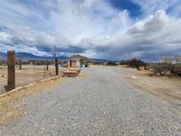 Desert property featuring a gravel driveway and small structure under a cloudy sky at 781 Buol Rd, Pahrump, NV 89048