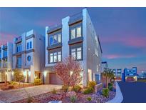 Modern three-story townhome with stucco facade and desert landscaping at dusk at 8178 Eaton Hill St, Las Vegas, NV 89113
