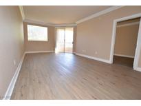 Bright living room featuring wood flooring, neutral walls, with a window and glass door leading to an outdoor space at 220 E Flamingo Rd # 116, Las Vegas, NV 89169