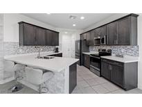 Modern kitchen features stainless steel appliances, mosaic backsplash, and quartz countertops with a breakfast bar at 5255 Peak Rock Ct, Las Vegas, NV 89141