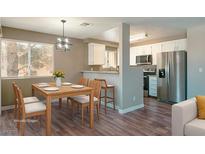Bright dining area with wood table and modern lighting fixture adjacent to the kitchen featuring stainless steel appliances at 6873 Tamarus St # 201, Las Vegas, NV 89119