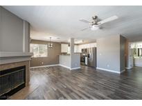 Open-concept living room with fireplace, ceiling fan, and wood-style floors flows to the kitchen at 6873 Tamarus St # 201, Las Vegas, NV 89119