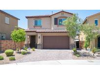 Two-story home features a desert landscape, a brick driveway, and a two-car garage at 871 Aurelie Ridge St, Henderson, NV 89011