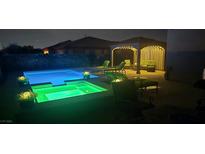Inviting backyard pool and spa with lounge area, pergola, and ambient lighting for relaxing evenings at 4242 Helena Hideaway Ct, Las Vegas, NV 89129