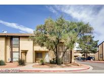 Charming townhome featuring a tan exterior, mature tree, and well-maintained landscaping at 499 Kristin Ln, Henderson, NV 89011