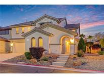 Inviting two-story home with arched entry, landscaping, and a charming facade at dusk at 733 Secret London Ave, Las Vegas, NV 89178