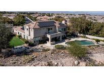 View of a luxury two-story house featuring a private pool and solar panels in a desert setting at 9301 Queen Charlotte Dr, Las Vegas, NV 89145