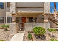 Inviting condo entrance featuring a gated courtyard, textured walls, and convenient stairs to the upper level at 1017 Falconhead Ln # 101, Las Vegas, NV 89128