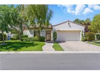 Charming single-story home with a manicured lawn, brick driveway, and lush, mature landscaping at 11775 Woodbrook Ct, Las Vegas, NV 89141